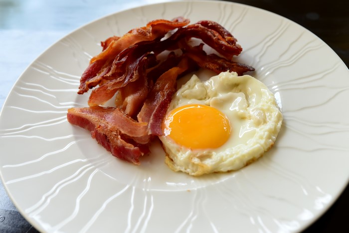 Fried egg and bacon on a white plate