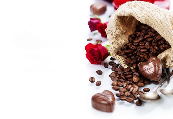 Coffee beans, chocolates, and roses spilling from a burlap sack