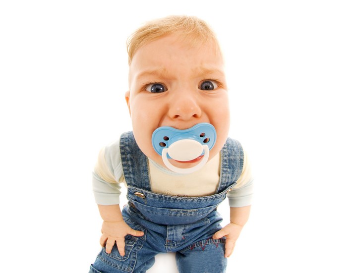 Baby boy with pacifier wearing denim overalls