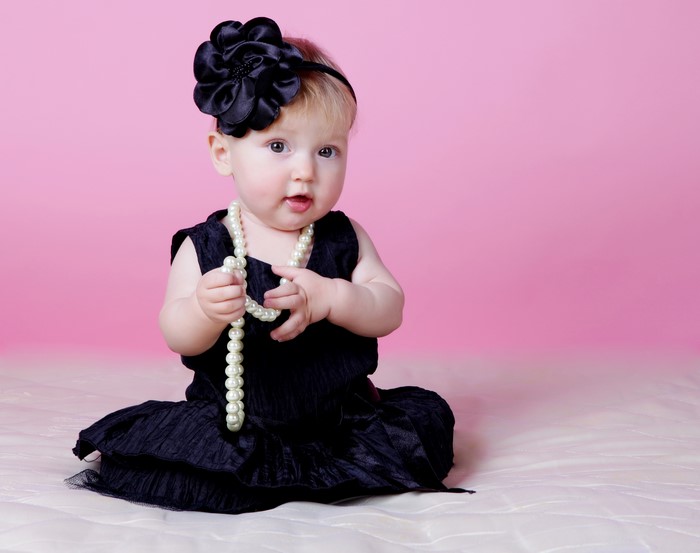 Baby girl in black dress with pearl necklace and flower headband