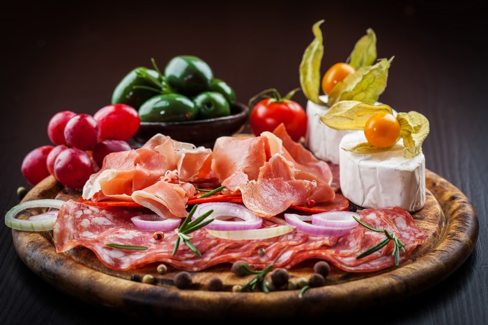 Charcuterie board with ham, salami, cheese, olives, and grapes
