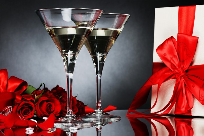 Two glasses of wine with roses and a gift