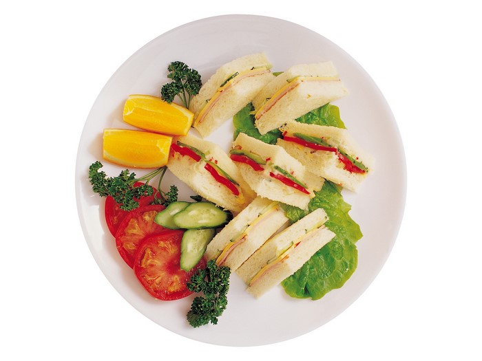 Sandwiches with tomatoes, cucumbers, and orange slices on a plate