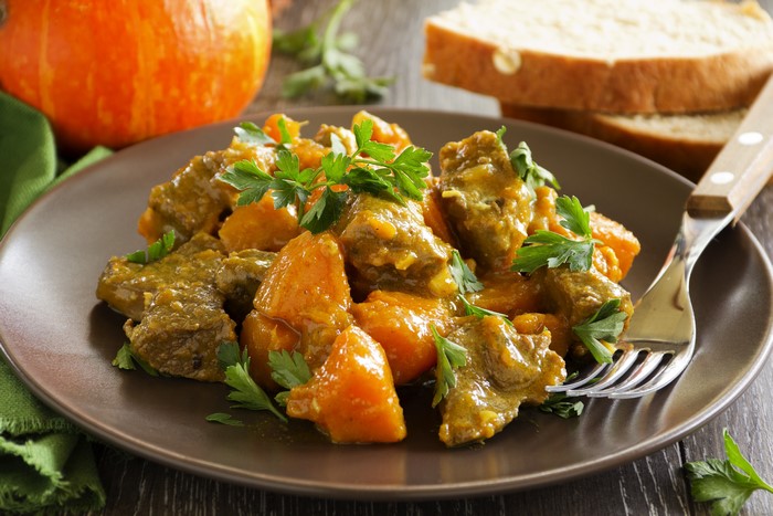 Meat and pumpkin stew on a plate with bread