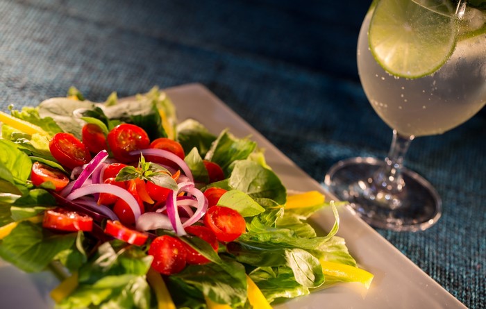 Salad with tomatoes and a drink with lime