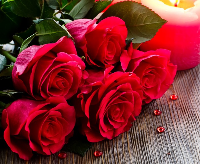 Red Roses and Candle on Wooden Surface