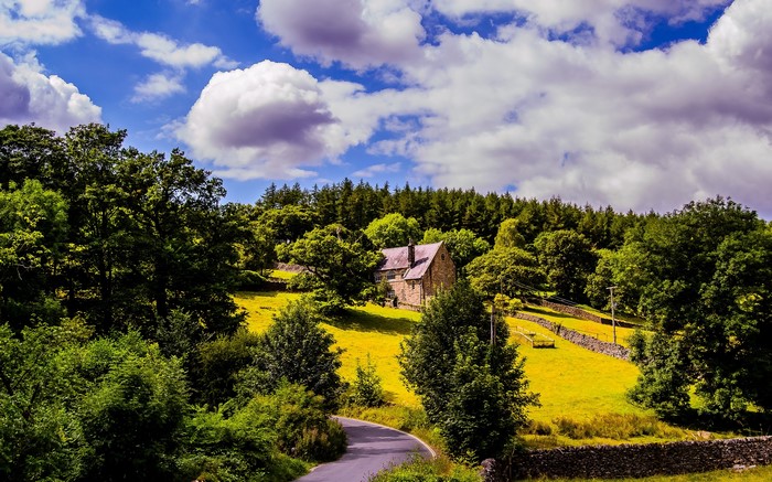 Stone house in a green landscape with clouds