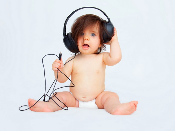 Infant wearing headphones and holding a cord