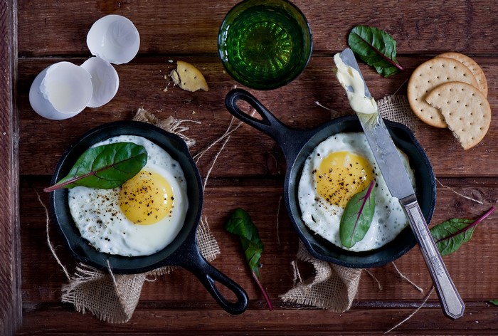 Fried eggs in cast iron pans with crackers and butter
