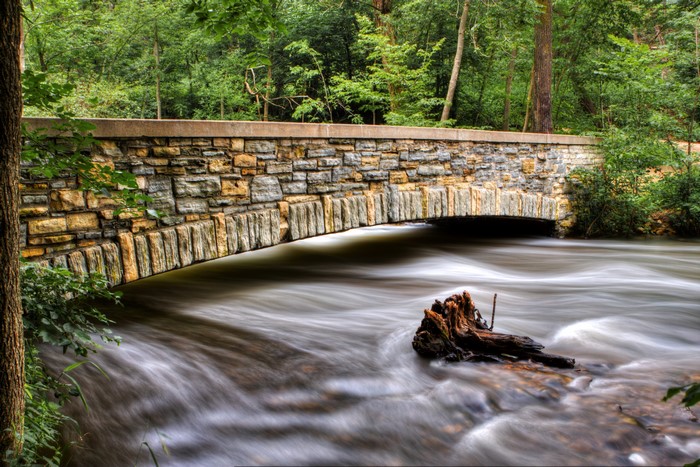 Stone bridge over a flowing river in a forest