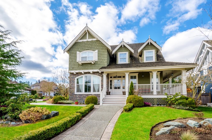 Green Shingled House with Stone Accents and Landscaped Lawn