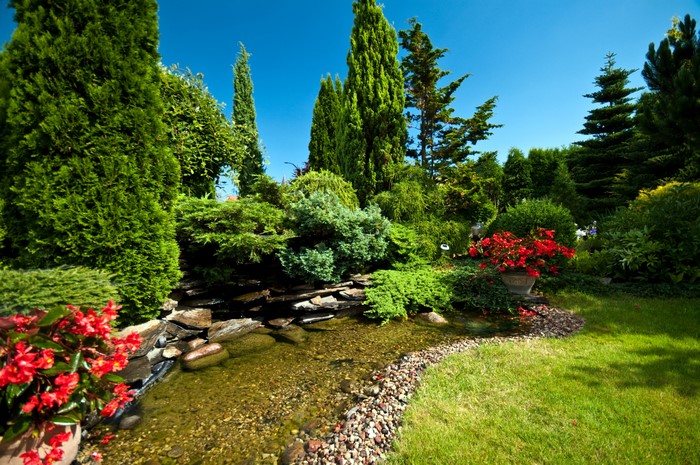 A beautifully landscaped garden with a stream and trees