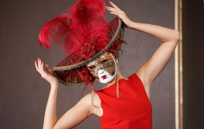 Woman in red dress wearing a Venetian mask and hat