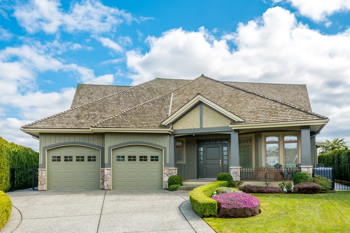 Green house with two garage doors and manicured lawn