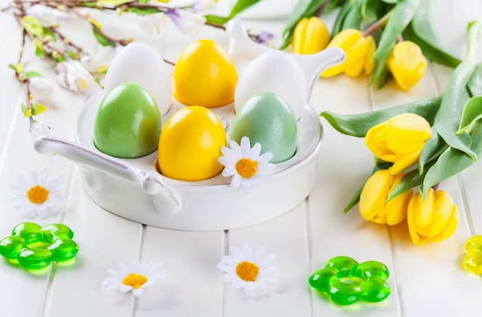 Easter eggs and yellow tulips on a white table
