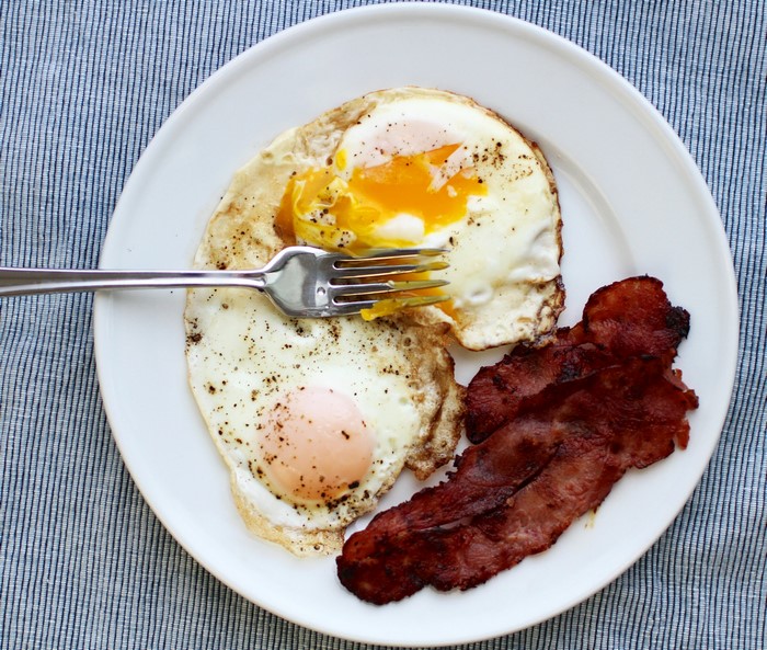 Fried eggs and bacon on a plate with a fork