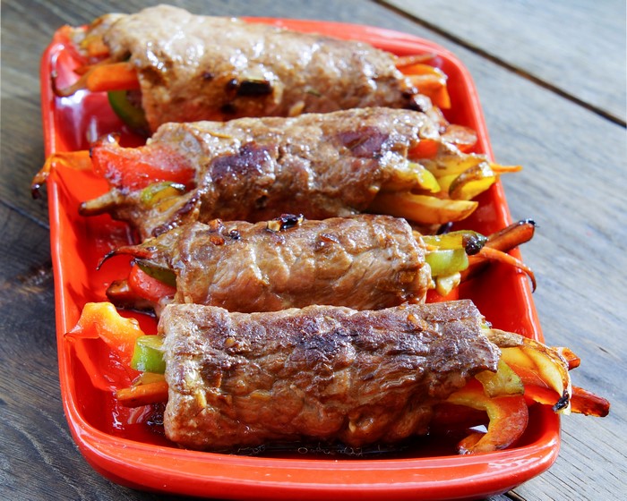 Meat rolls with bell peppers on a red plate