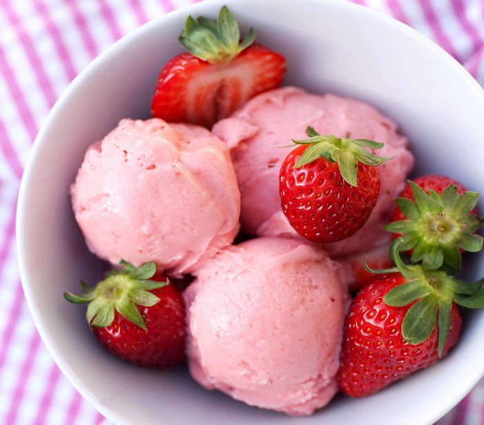 Strawberry ice cream in a bowl with fresh strawberries