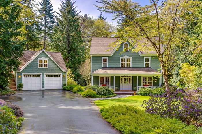 Green house with attached garage and trees