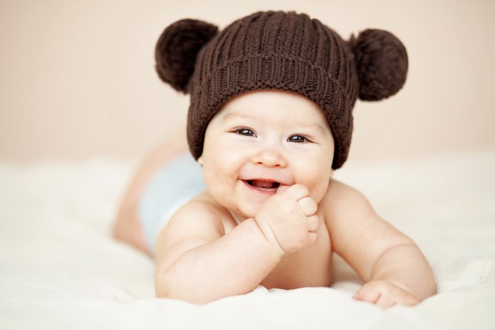 Baby wearing a brown bear hat smiling