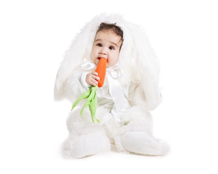 Baby in a bunny costume eating a carrot