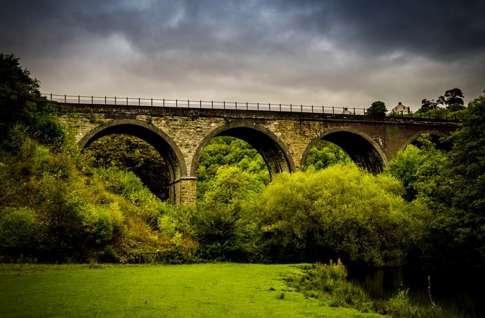 Stone railway viaduct over a green valley in Derbyshire, UK