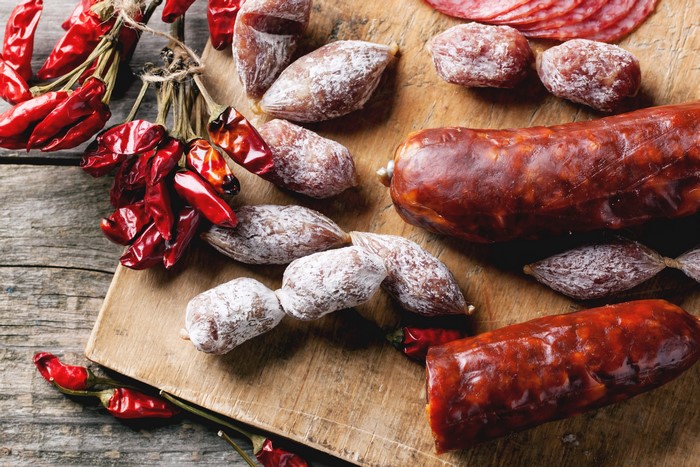 Sausages and dried chili peppers on a wooden board