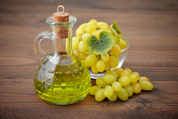 Grape seed oil in a jug with grapes