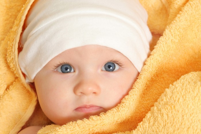 Baby wearing a winter hat wrapped in a yellow towel