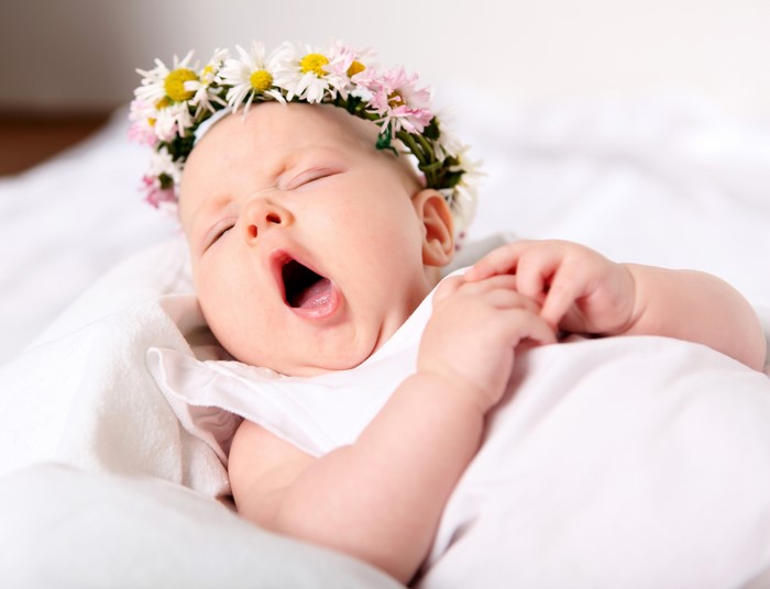 Baby wearing a flower crown yawning