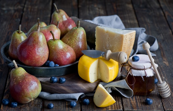 Pears, cheese, blueberries, and honey on a wooden table