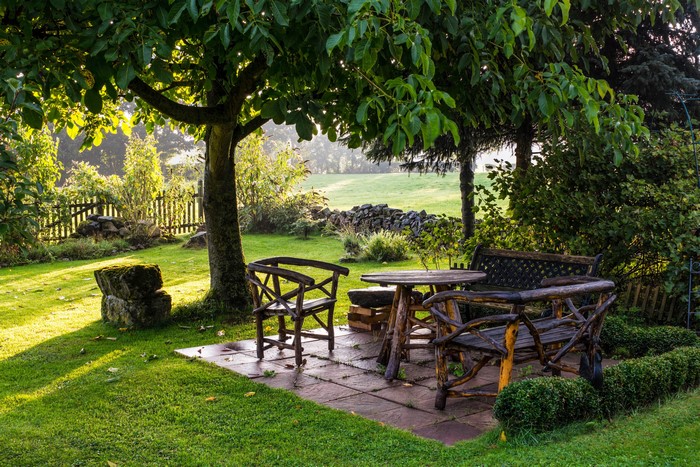 Garden with rustic wooden furniture under a tree