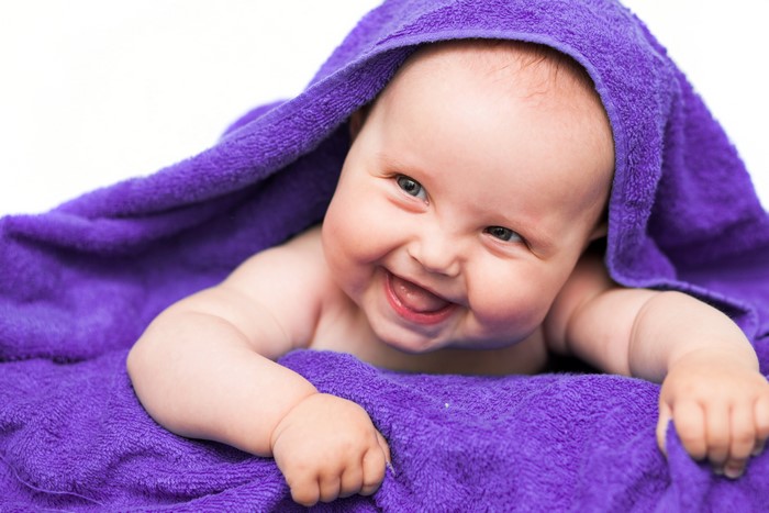 Baby wrapped in a purple towel smiling