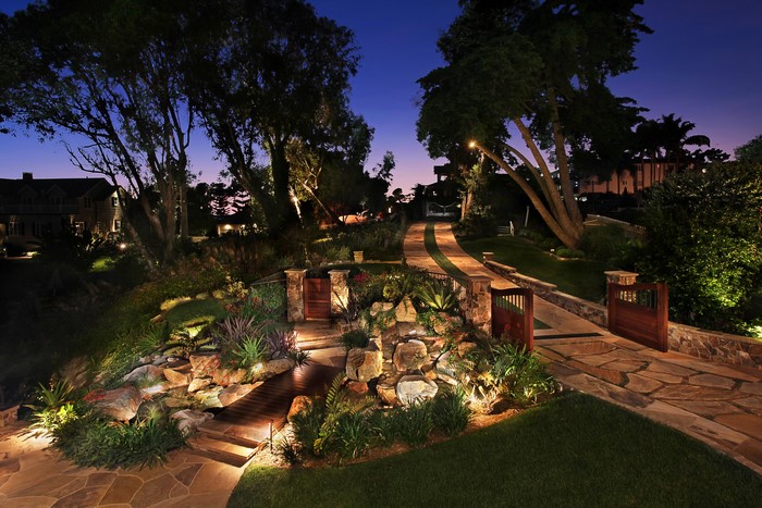 Illuminated garden path and waterfall at dusk