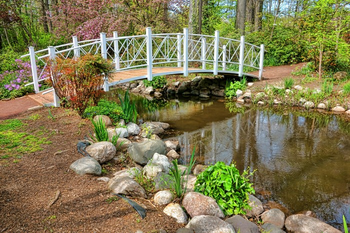 White arched bridge over a pond in a park during spring