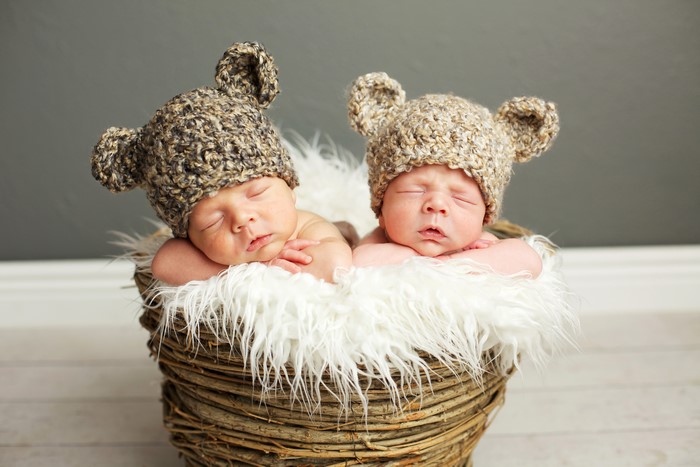 Two sleeping infants in bear hats in a basket