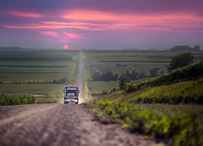 Truck driving on a dirt road at sunset