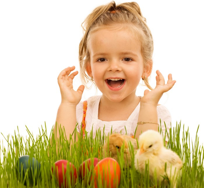 Little girl with Easter chicks and eggs in grass