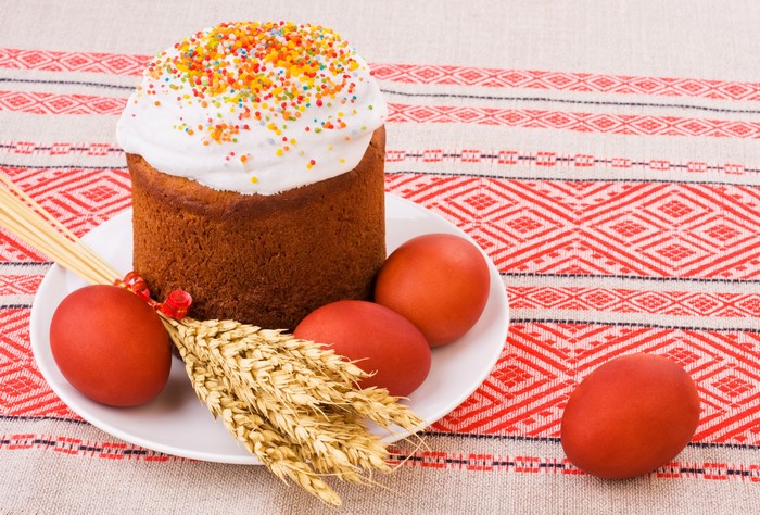 Easter Kulich with red eggs and wheat on a patterned tablecloth