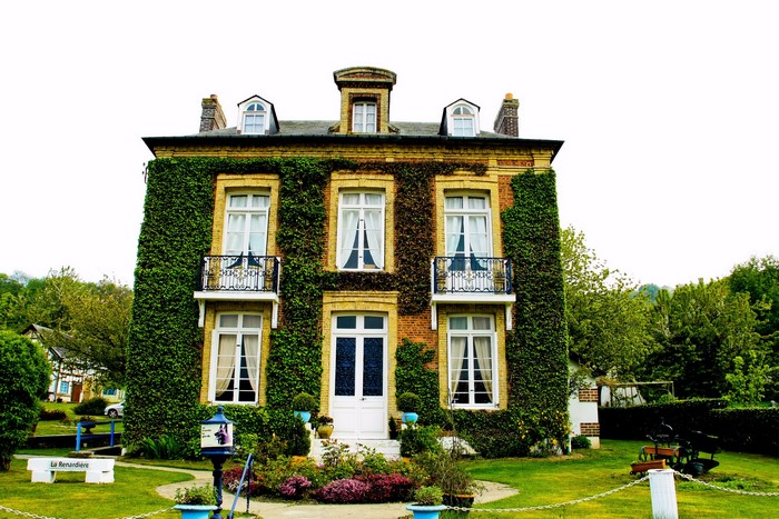 Brick house covered in ivy with balconies and dormer windows
