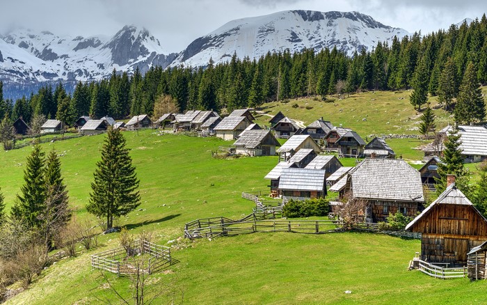 Mountain village with wooden houses and snowy peaks in Slovenia