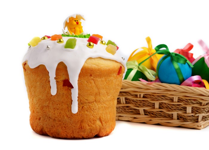 Easter Kulich with Icing and Candied Fruit in a Wicker Basket with Eggs