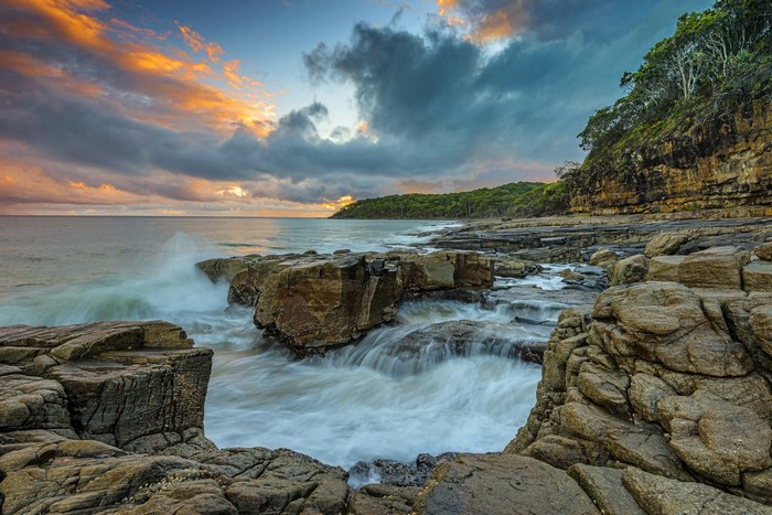 Rocky coast with waves crashing during sunset in Queensland, Australia