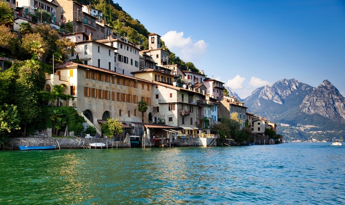 Houses on a hillside by a lake with mountains