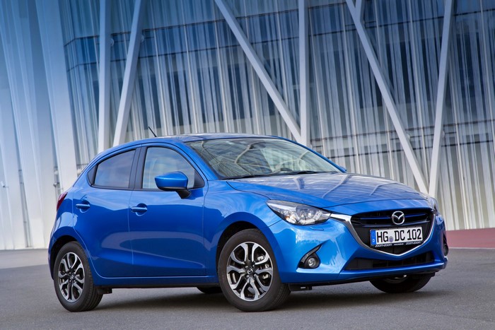 Blue Mazda 2 Hatchback parked in front of a modern building