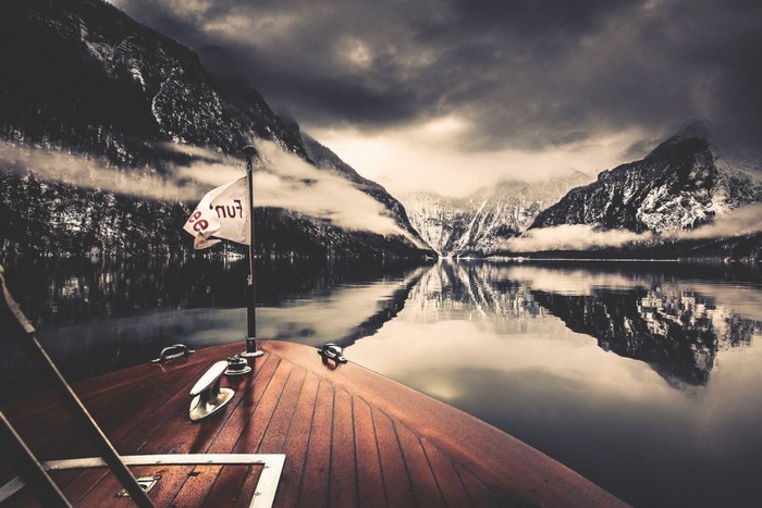 Boat on a lake with mountains and clouds