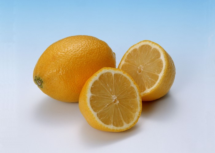 Whole and halved lemons on a blue background