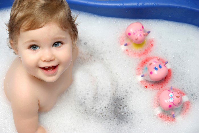 Baby girl in a bubble bath with toys