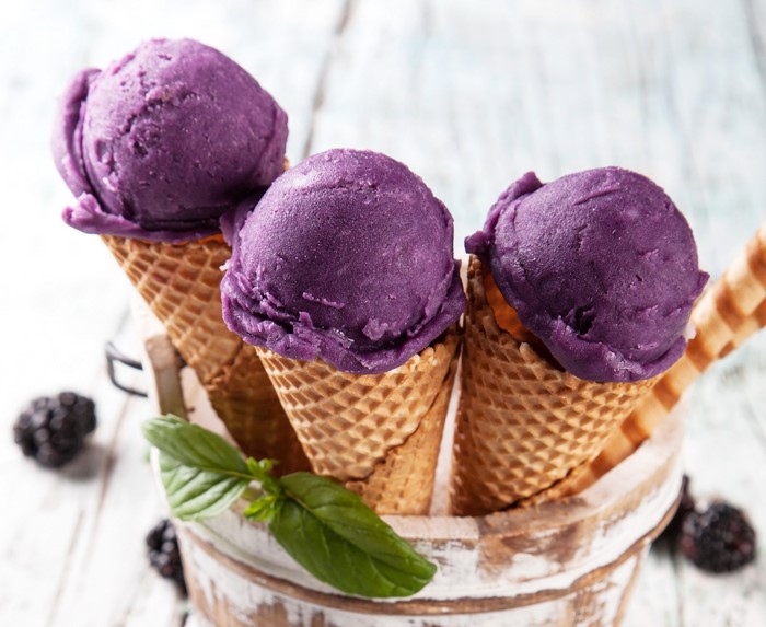Three purple ice cream cones with blackberries and basil