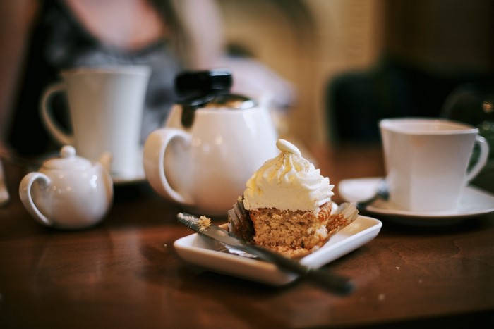Cupcake with frosting and tea set on a table